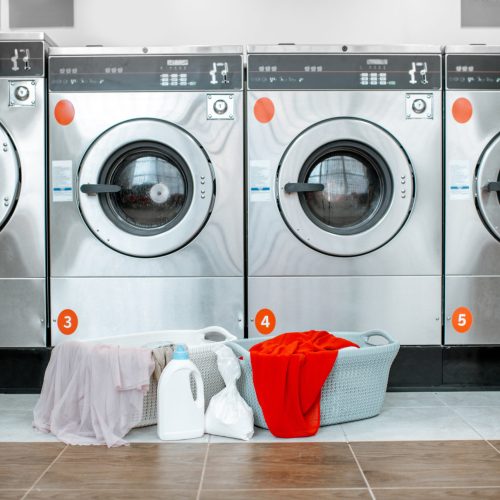 Professional washing machines with baskets full of clothes at the self-service laundry